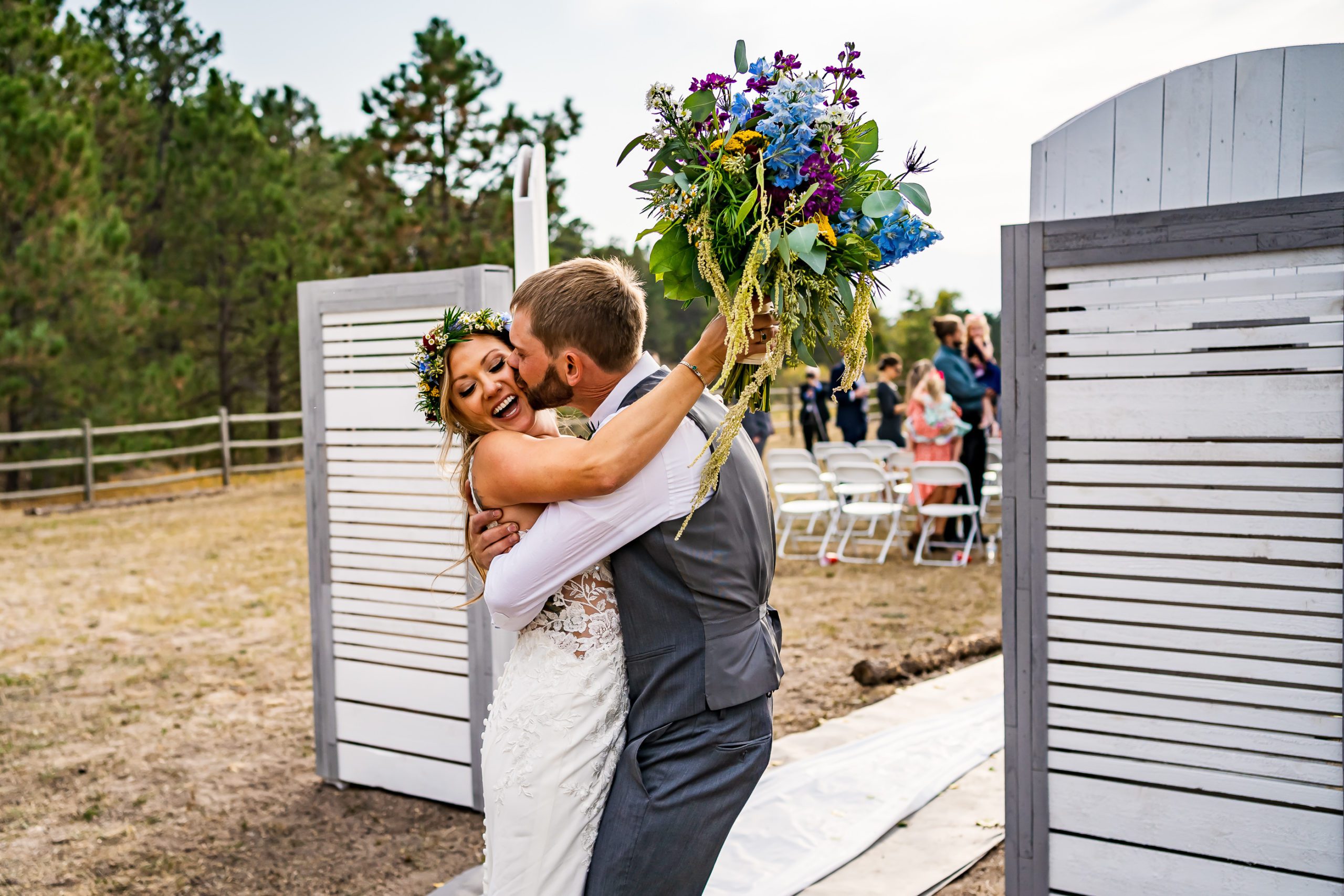 A groom kisses his bride after their backyard wedding ceremony.