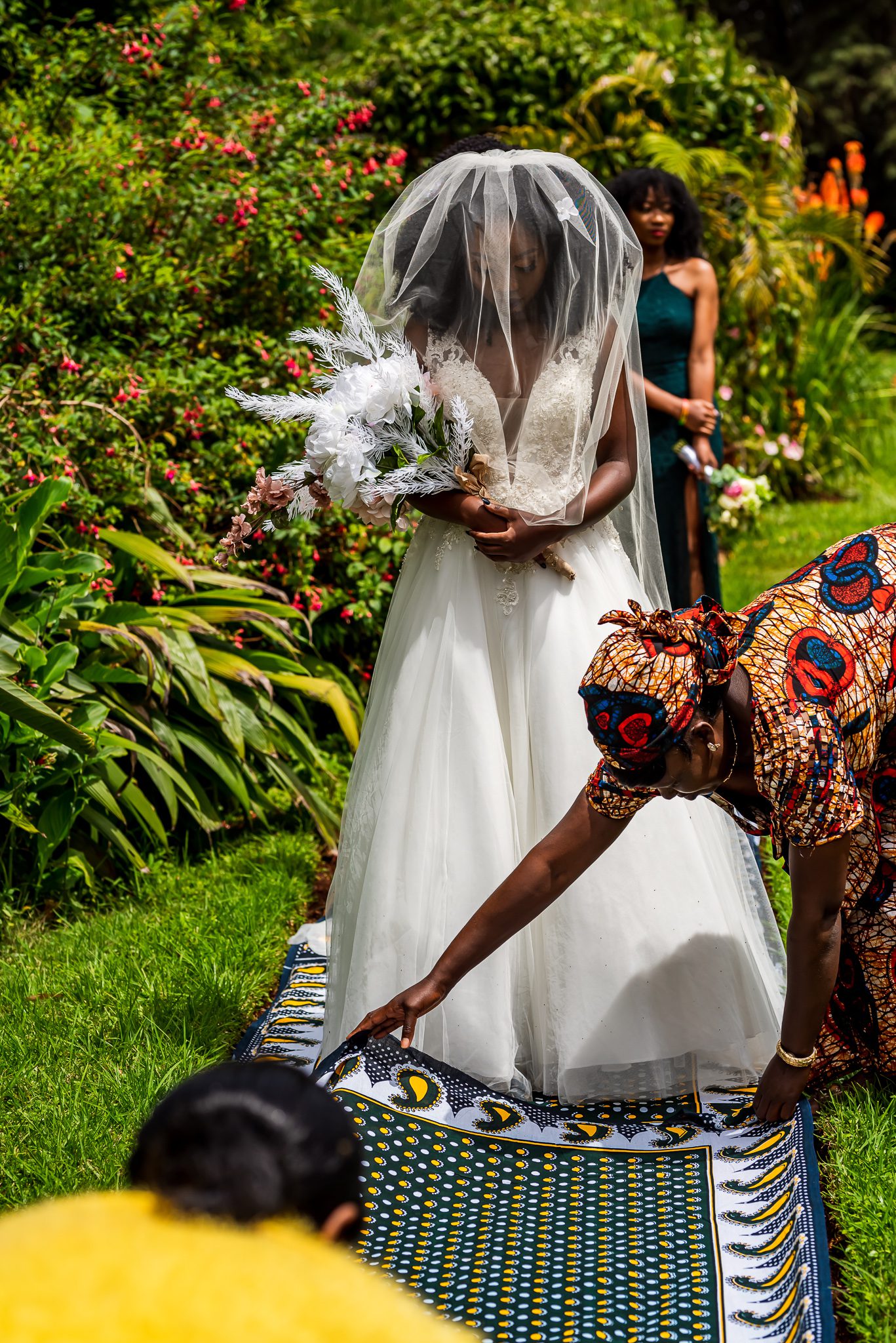 a woman lays a cloth down on the ground in front of a bride before she walks down the isle