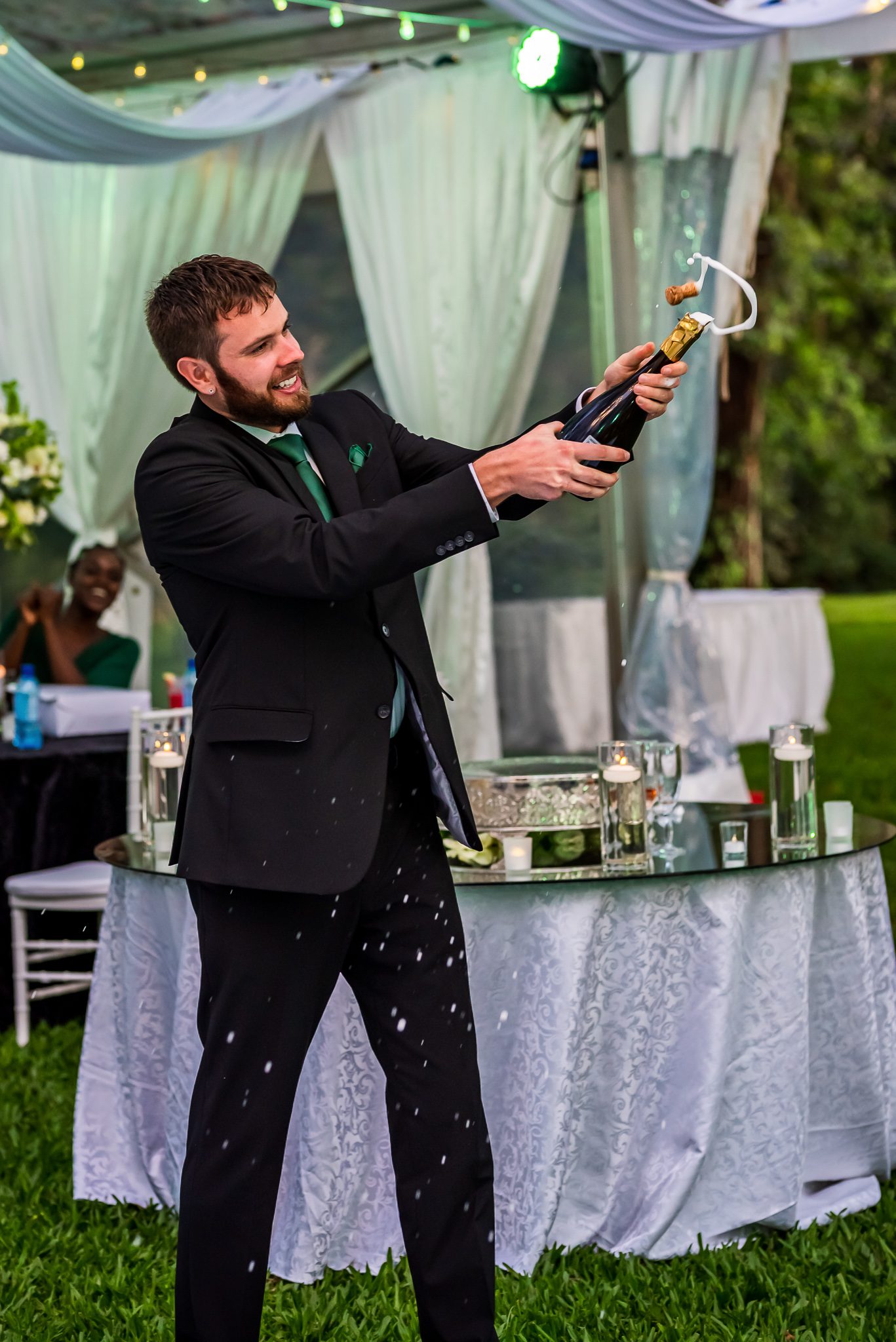 a man pops a champagne bottle at a wedding reception