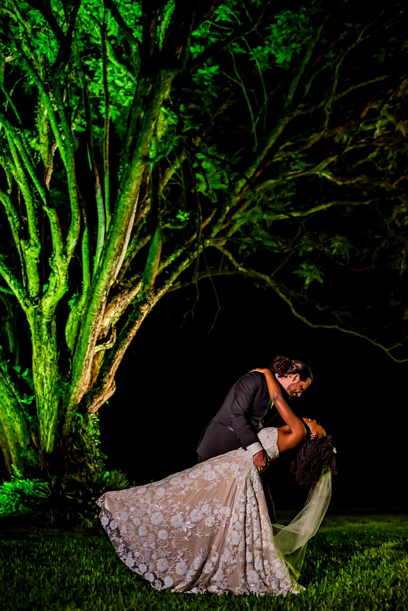 a groom dips his bride and kisses her outside a night