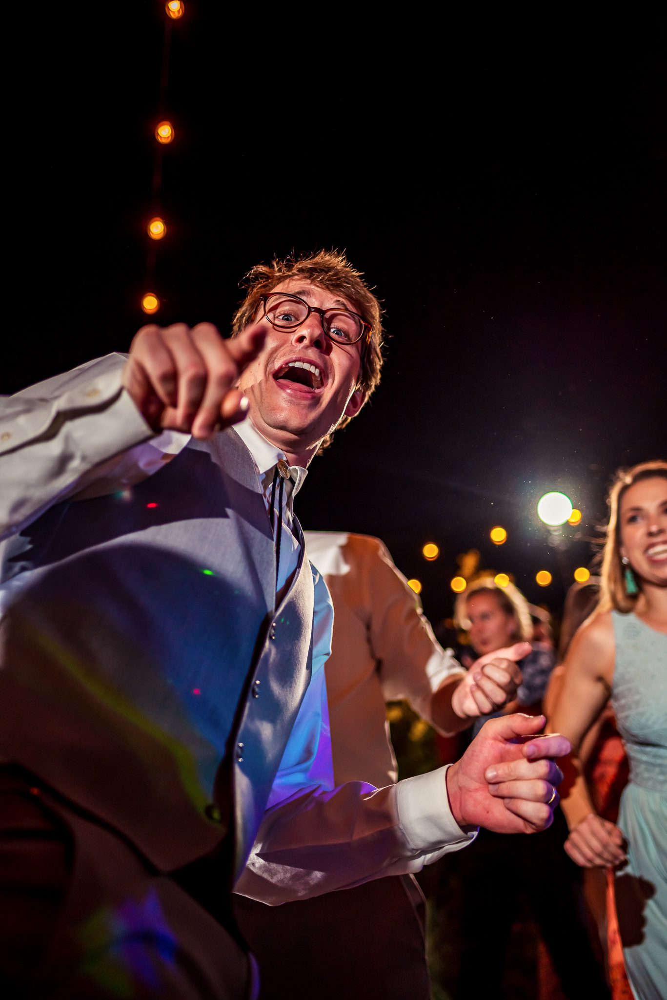 A man points into the camera as he dances during a wedding reception