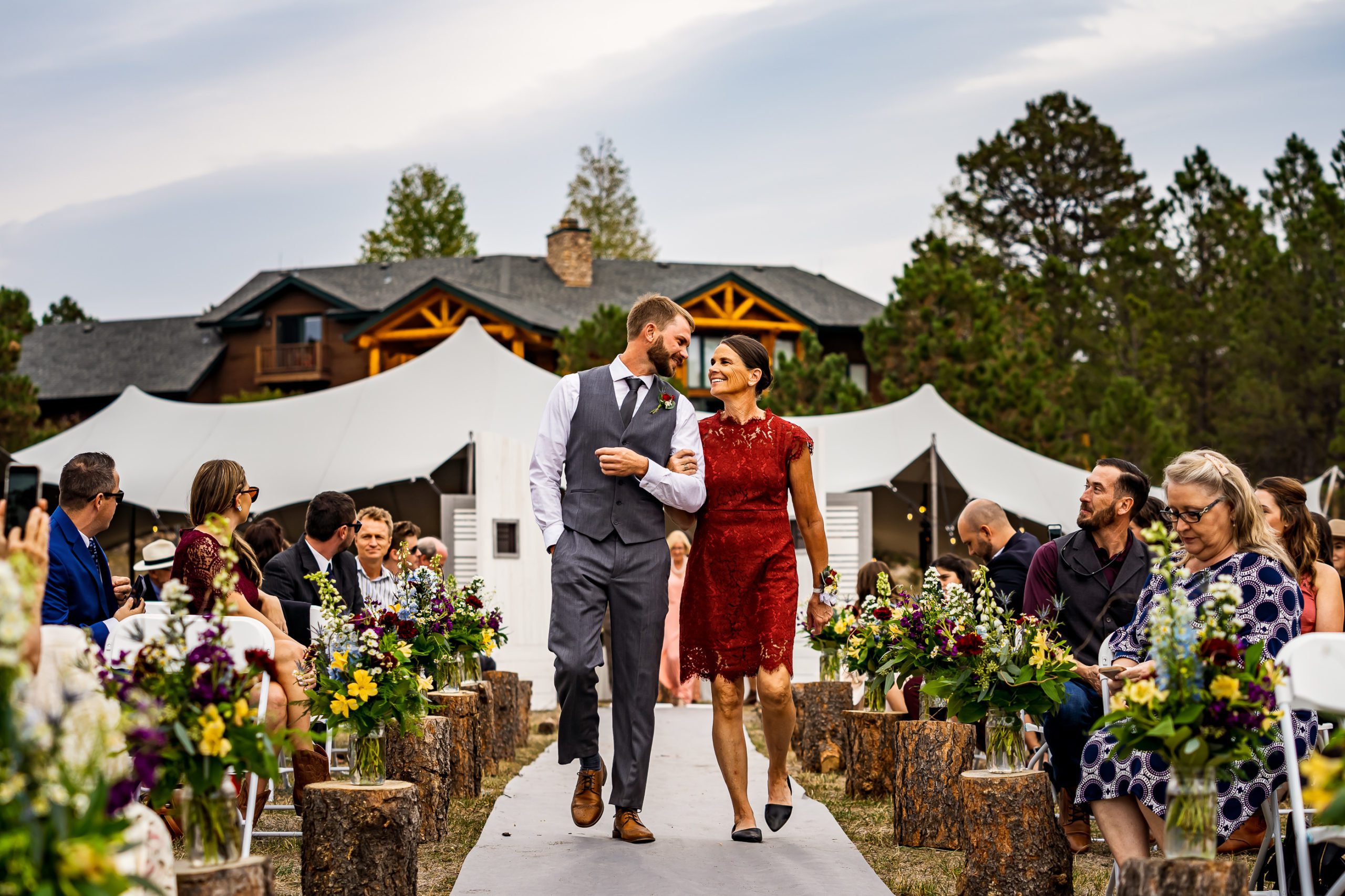 A bridesmaid and groomsman walk down the isle at a backyard wedding in Colorado.