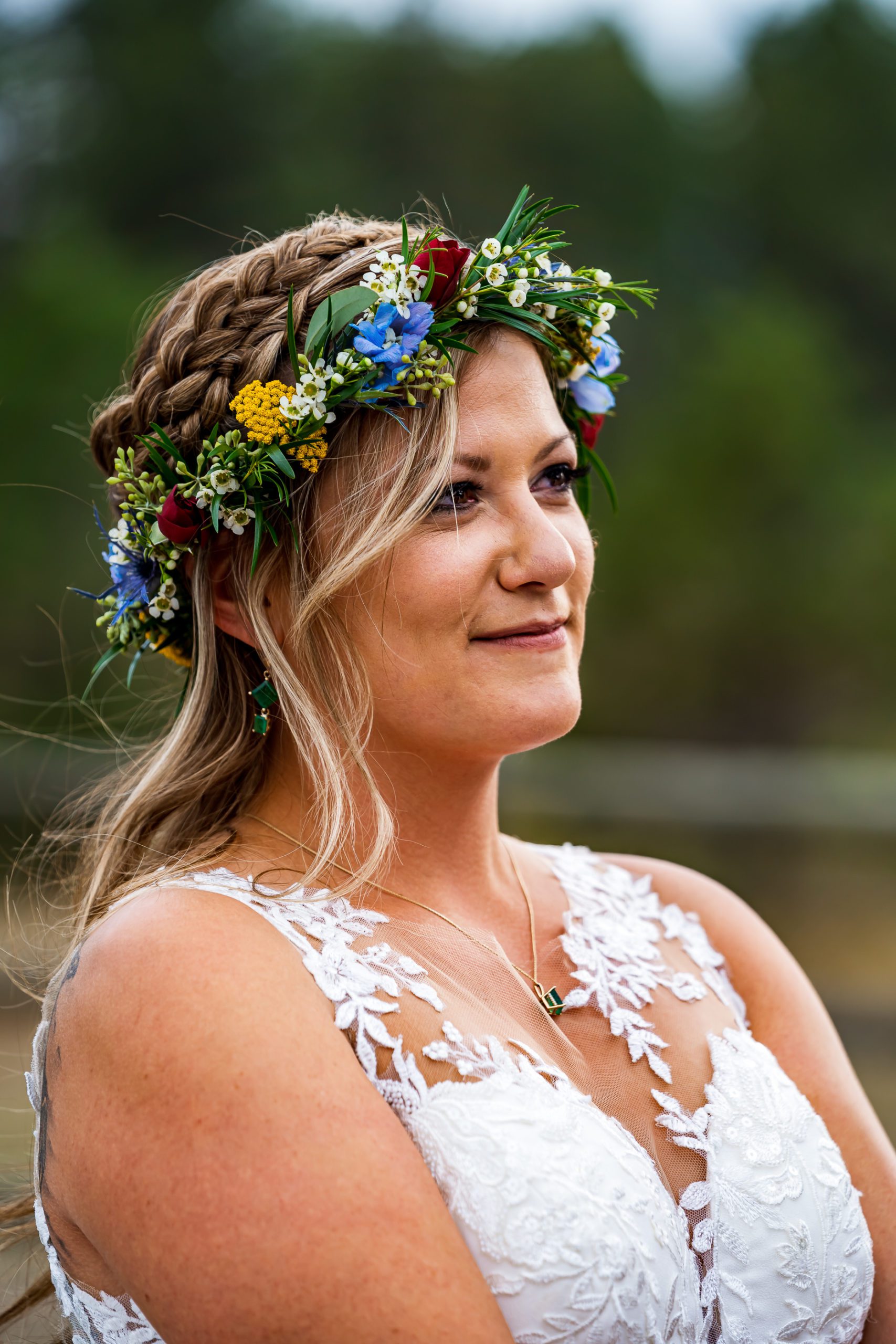A bride with blonde hair, white dress and blue and yellow flower crown.