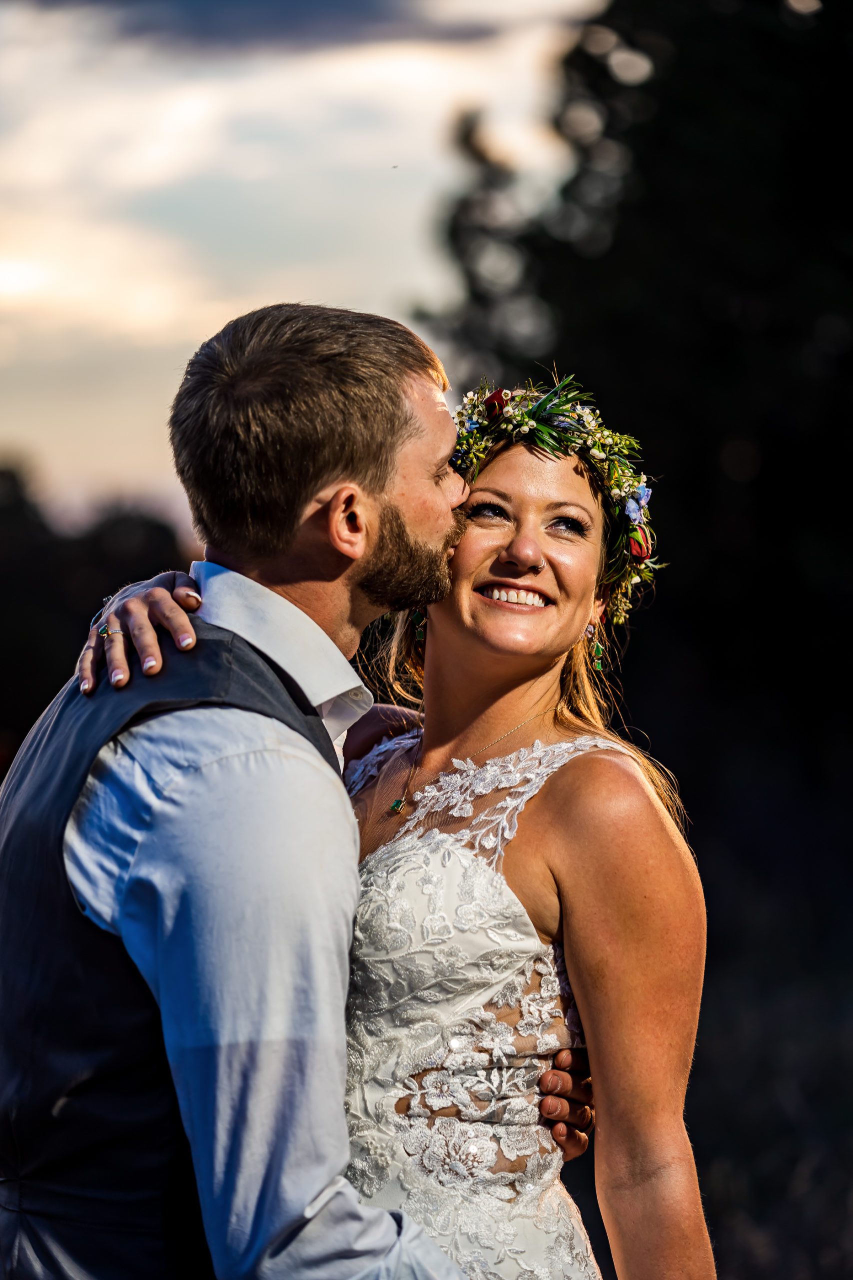 a groom kisses his bride wearing a flower crown on their wedding day